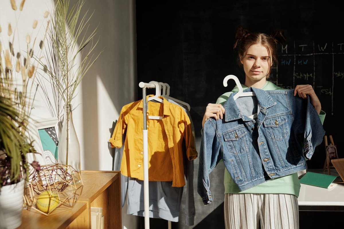 Seller holding up a vintage denim jacket on a hanger in daylight to photograph it for a listing